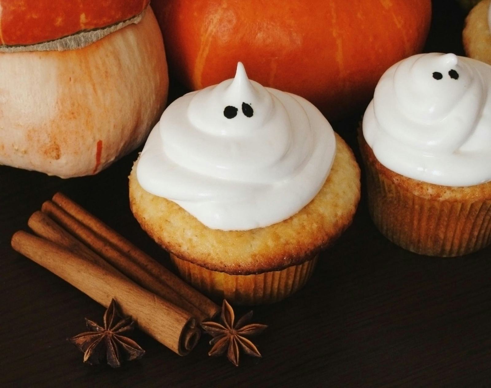 Pumpkin muffins topped with meringue ghosts, pumpkins and cinnamon sticks