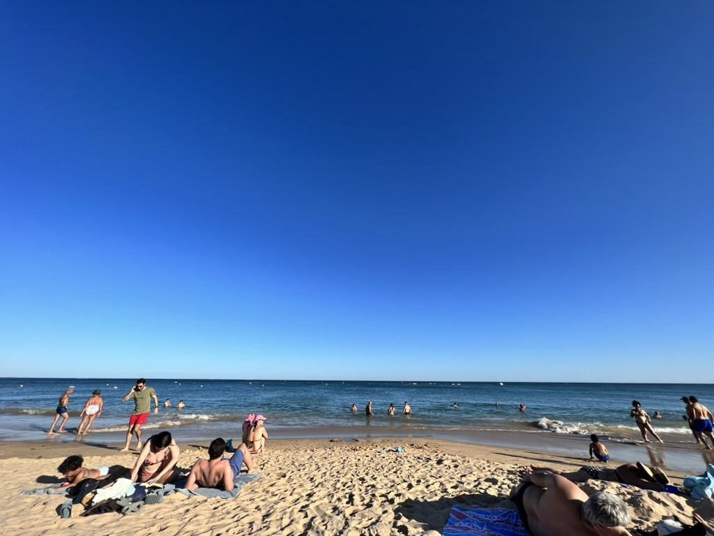 Sunbathers and swimmers on Santa Eulália Beach in Albufeira on a clear summer afternoon