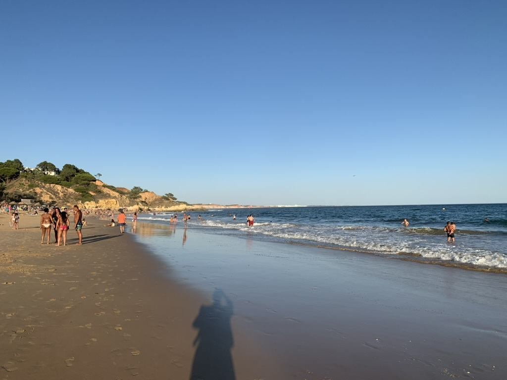 Praia de Santa Eulália, em Albufeira, com areal dourado, banhistas e mar azul ao fim da tarde