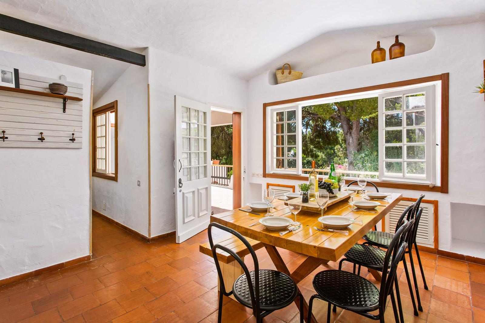 Sala de jantar com mesa de madeira e janela para os pinheiros