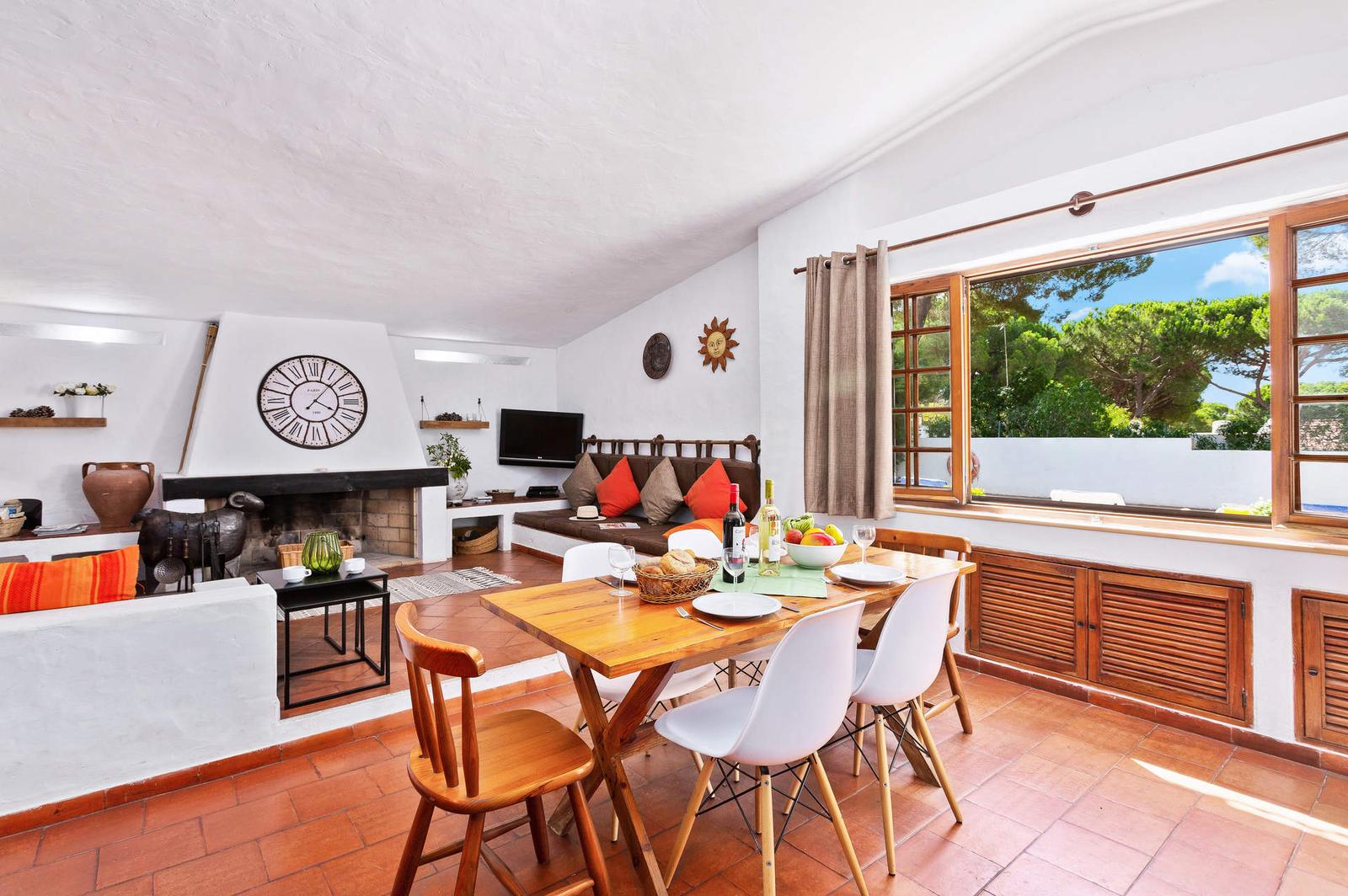 Sala de estar com lareira e mesa de jantar da Villa Simão